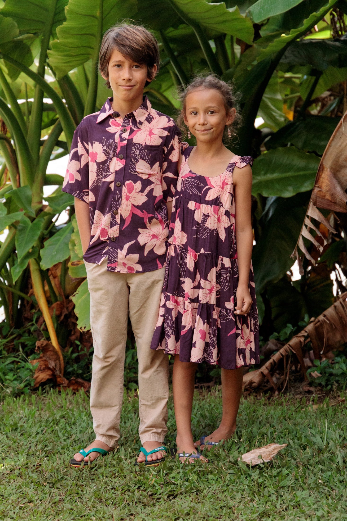 little boy wearing a dark purple aloha button up shirt with orchid print