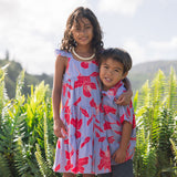 little boy with brown hair wearing a button up aloha shirt with periwinkle background and bright red hibiscus print.