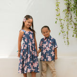 little boy wearing button up aloha shirt in navy and pink hibiscus print.