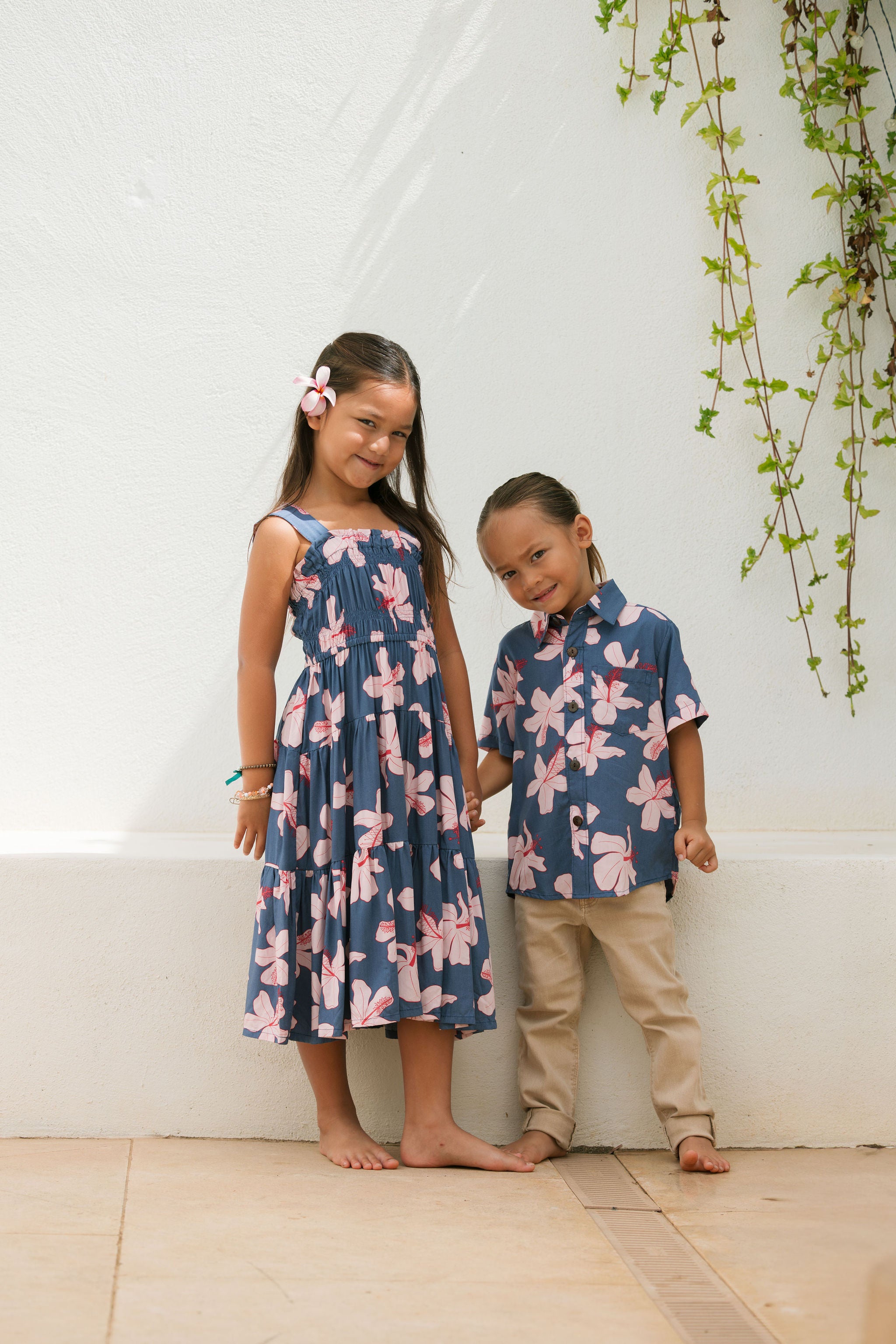 little girl wearing a tiered maxi dress in navy and pink hibiscus print.