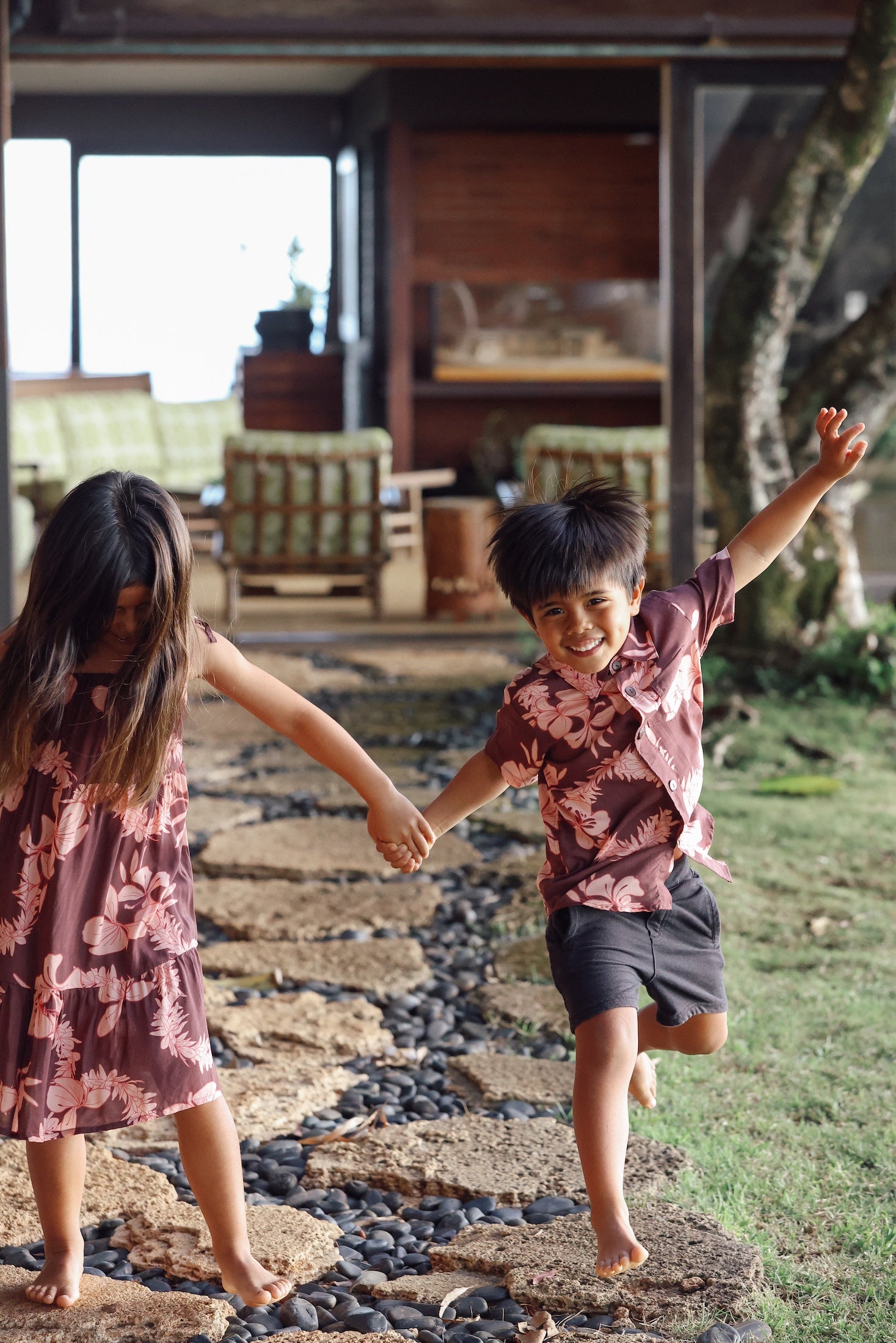 little boy wearing brown aloha shirt with pink lei awapuhi print