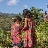 girl with brown hair wearing a colorful dress with tropical lei print