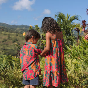 girl with brown hair wearing a colorful dress with tropical lei print