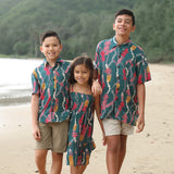 little boy wearing aloha button up shirt in dark teal with shell and lei print