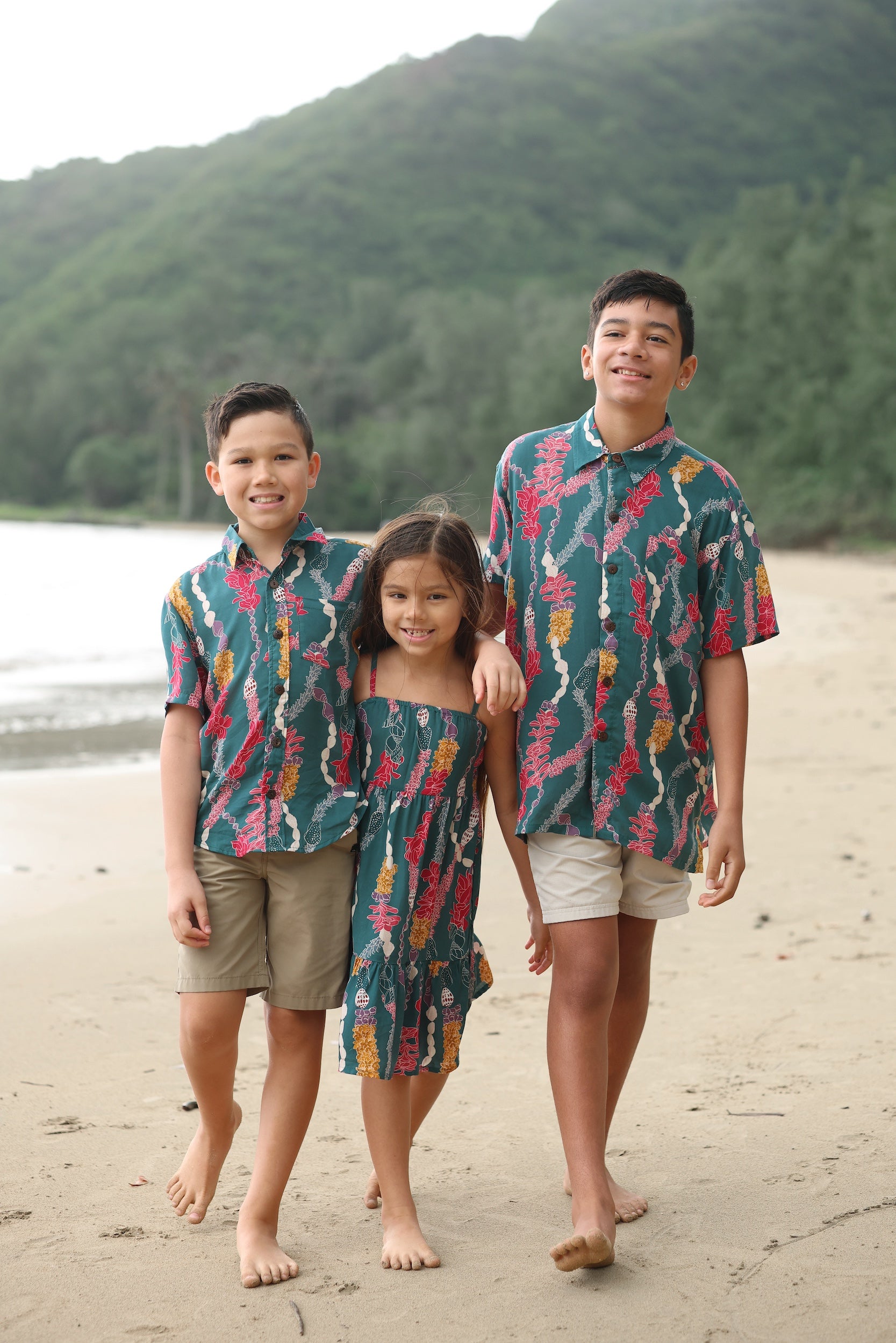 little boy wearing aloha button up shirt in dark teal with shell and lei print