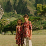 boy wearing red-brown aloha button up shirt with lei print