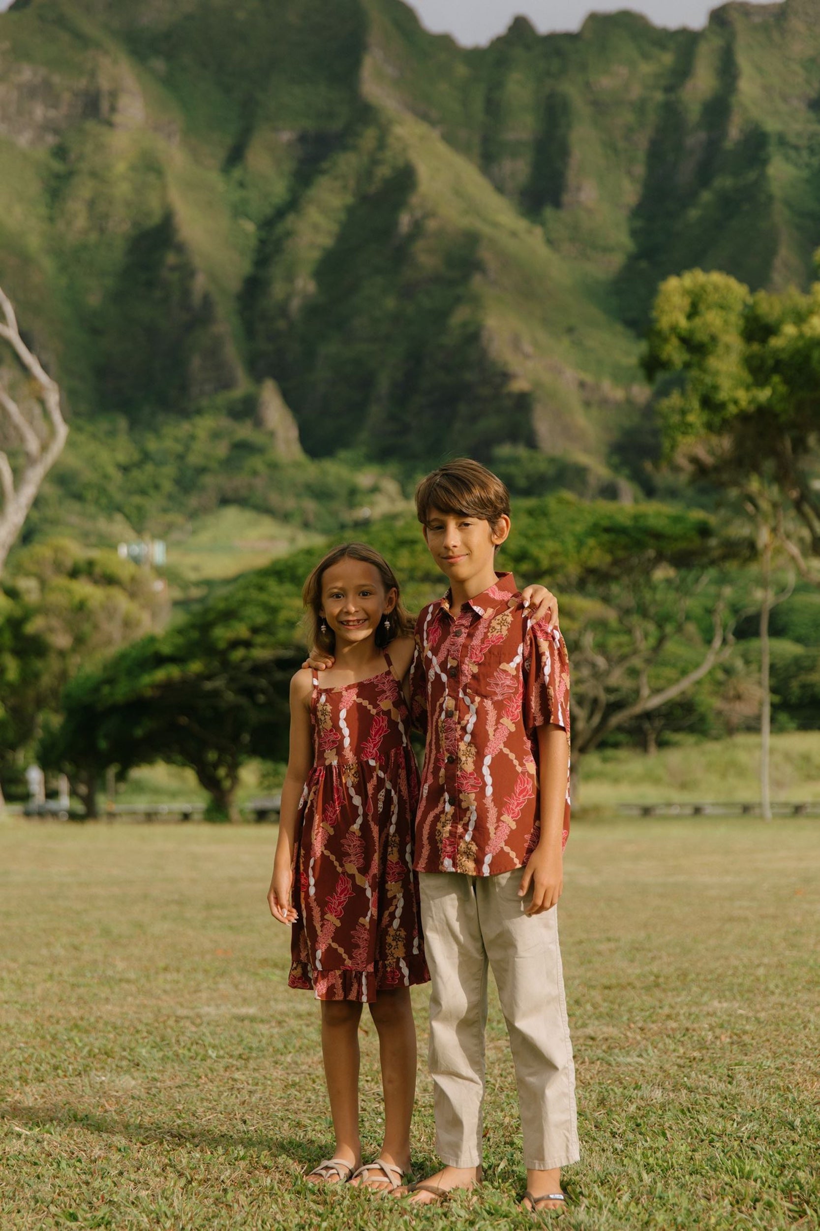 boy wearing red-brown aloha button up shirt with lei print