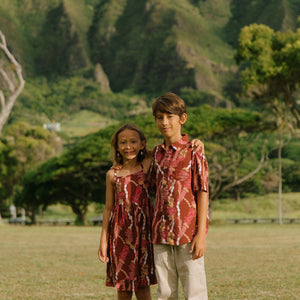 boy wearing red-brown aloha button up shirt with lei print