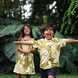 little boy wearing mini aloha button up shirt in green print and naupaka pattern