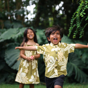 little boy wearing mini aloha button up shirt in green print and naupaka pattern