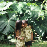 little girl wearing spaghetti strap dress in green print with naupaka pattern