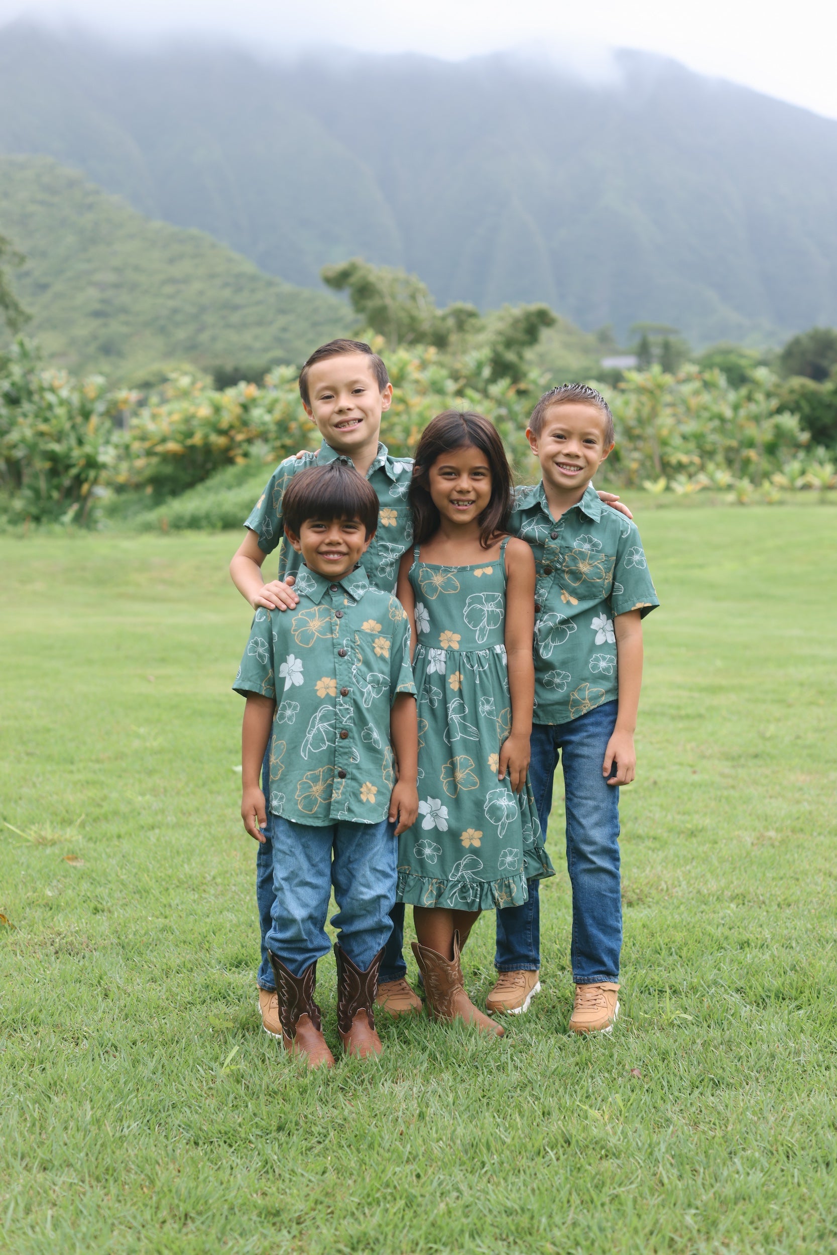 little girl wearing lush green tie back dress with puakenikeni print