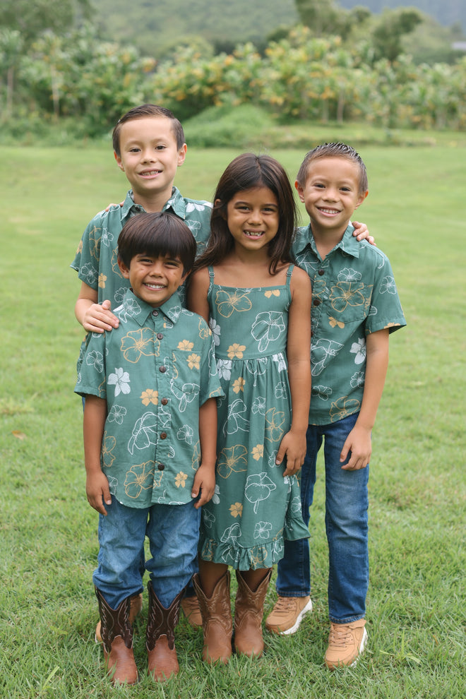 little girl wearing lush green tie back dress with puakenikeni print