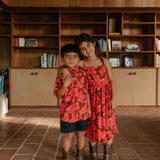 little girl wearing tie back dress with retro pink pua pattern