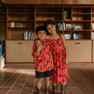 little girl wearing tie back dress with retro pink pua pattern