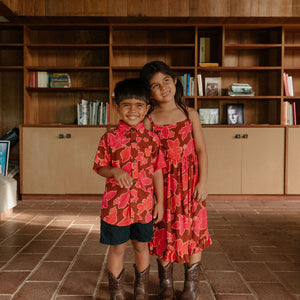 litte boy wearing aloha button up shirt with vibrant pink pua pattern
