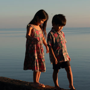 little girl wearing a teal dress with flutter sleeves with shell and pua print