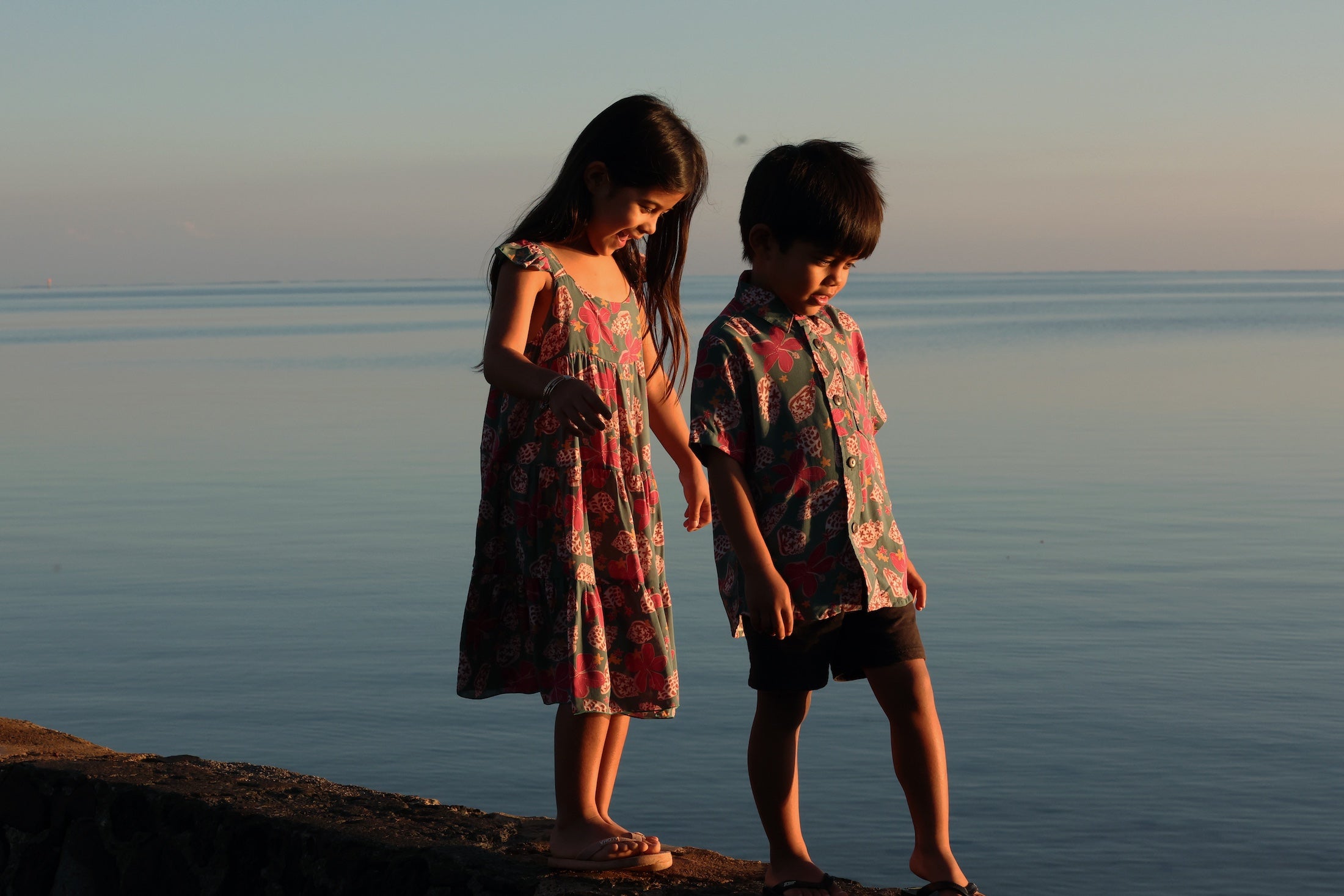 little girl wearing a teal dress with flutter sleeves with shell and pua print
