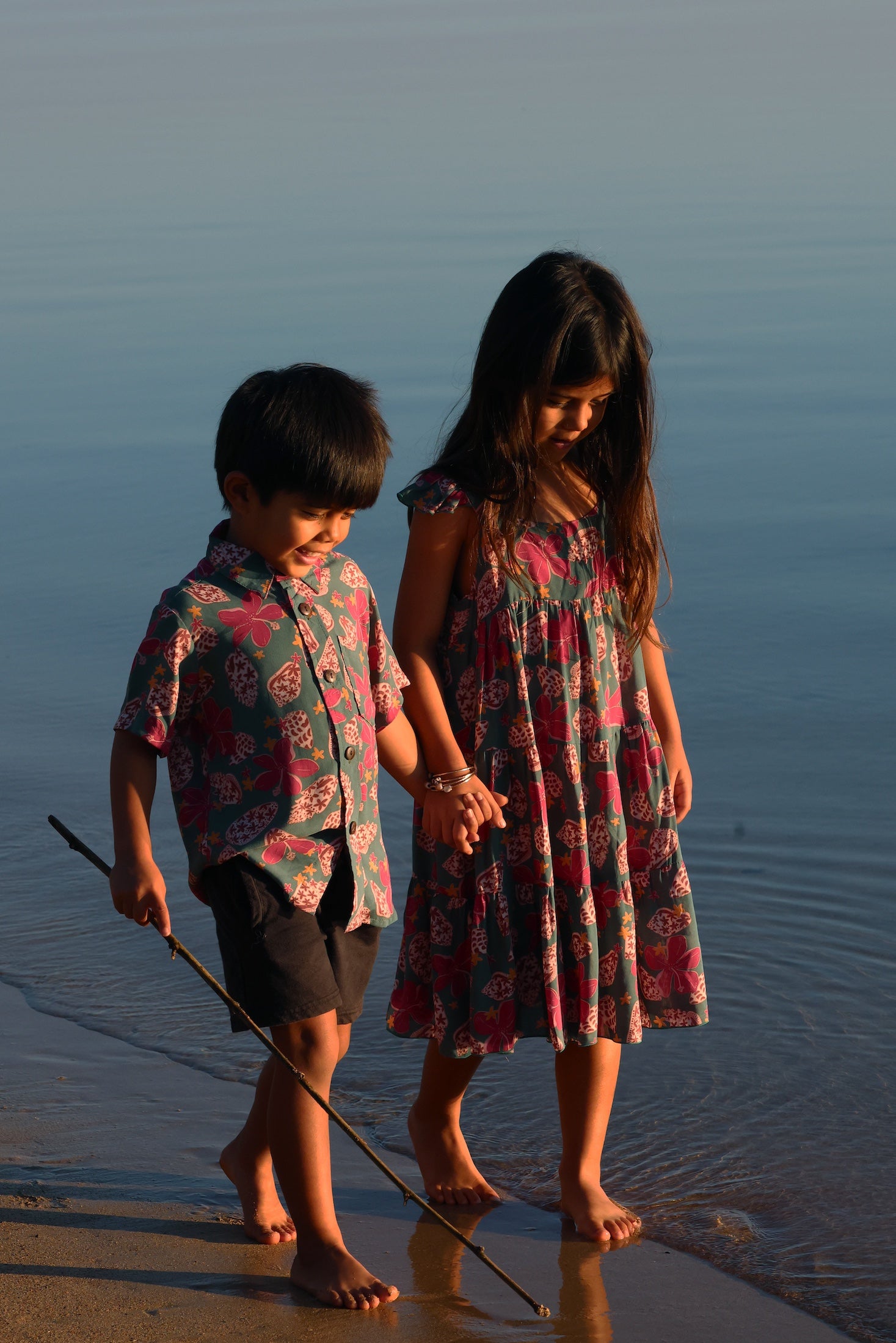 little girl wearing a teal dress with flutter sleeves with shell and pua print