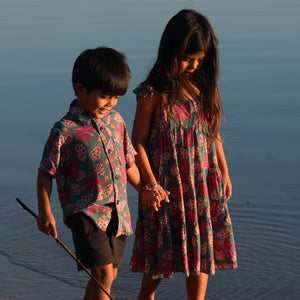 little girl wearing a teal dress with flutter sleeves with shell and pua print