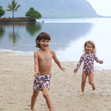 little girl wearing long sleeve one piece bikini in blush and brown hibiscus print.