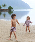 little girl wearing long sleeve one piece bikini in blush and brown hibiscus print.