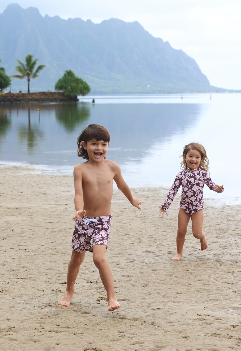 little girl wearing long sleeve one piece bikini in blush and brown hibiscus print.