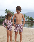 little girl wearing long sleeve one piece bikini in blush and brown hibiscus print.