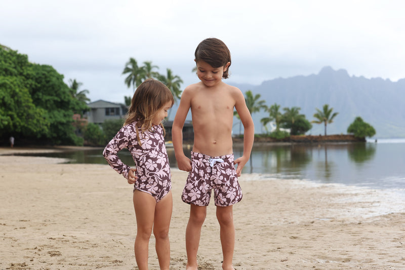little girl wearing long sleeve one piece bikini in blush and brown hibiscus print.