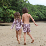 little girl wearing long sleeve one piece bikini in blush and brown hibiscus print.