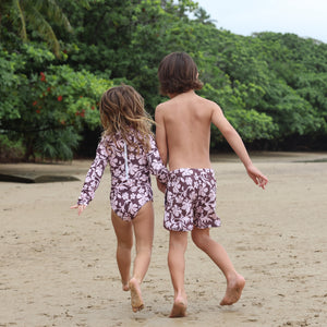 little girl wearing long sleeve one piece bikini in blush and brown hibiscus print.