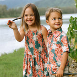 little girl wearing a knee length dress with red ginger and tiare print