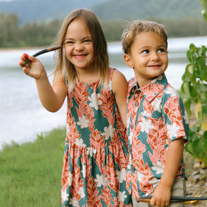 little girl wearing a knee length dress with red ginger and tiare print