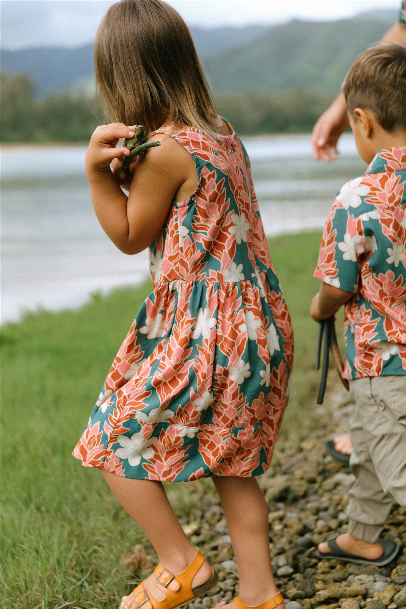 little girl wearing a knee length dress with red ginger and tiare print