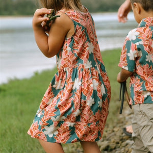 little girl wearing a knee length dress with red ginger and tiare print