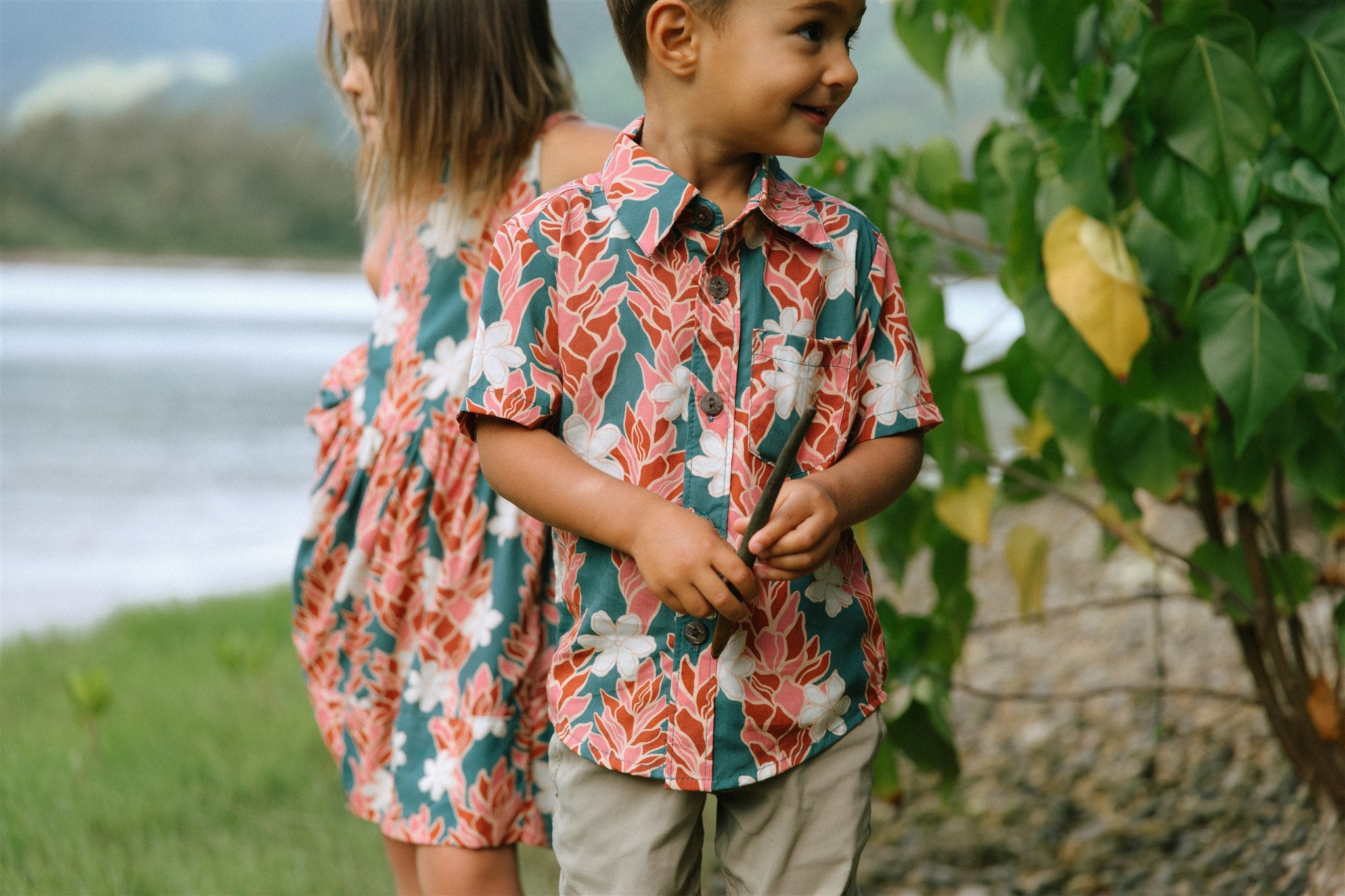 little boy wearing an aloha button up shirt with red ginger and tiare print
