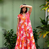 woman with brown hair wearing a pink short sleeve tiered maxi dress with retro flower print