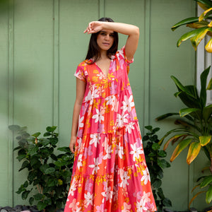 woman with brown hair wearing a pink short sleeve tiered maxi dress with retro flower print