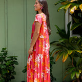 woman with brown hair wearing a pink short sleeve tiered maxi dress with retro flower print