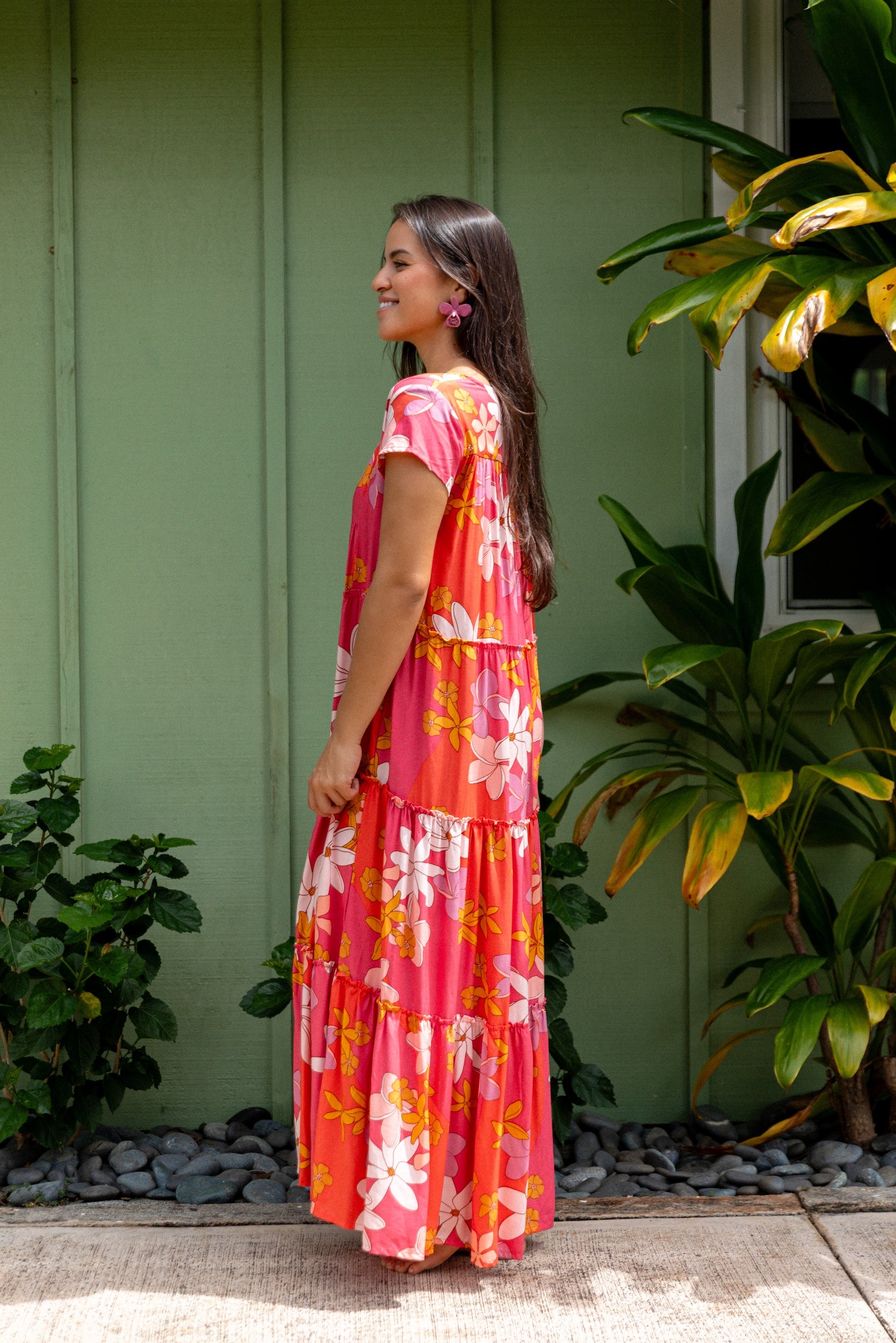 woman with brown hair wearing a pink short sleeve tiered maxi dress with retro flower print