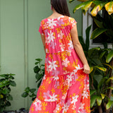 woman with brown hair wearing a pink short sleeve tiered maxi dress with retro flower print