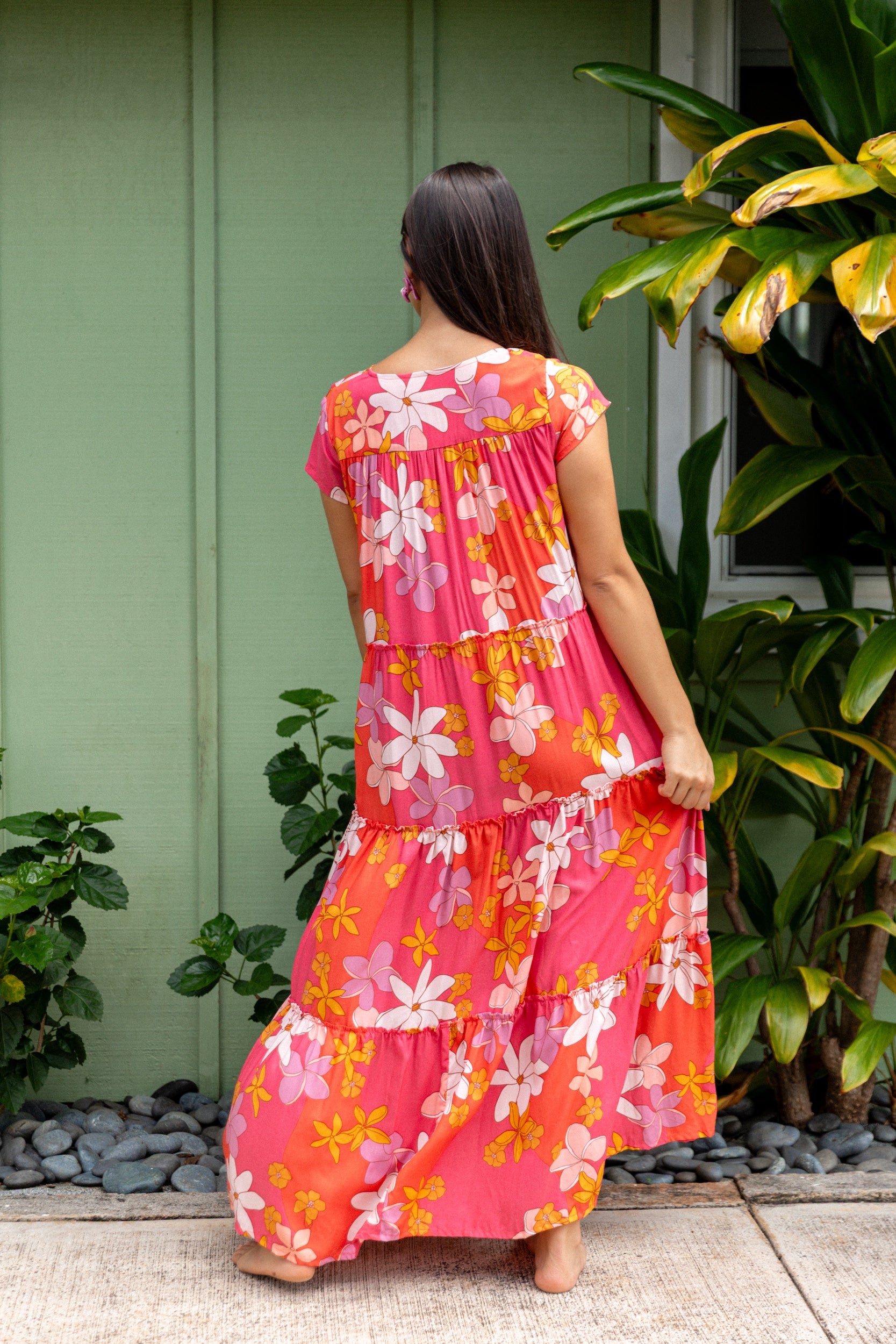 woman with brown hair wearing a pink short sleeve tiered maxi dress with retro flower print