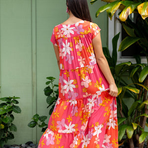 woman with brown hair wearing a pink short sleeve tiered maxi dress with retro flower print