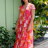 woman with brown hair wearing a pink short sleeve tiered maxi dress with retro flower print