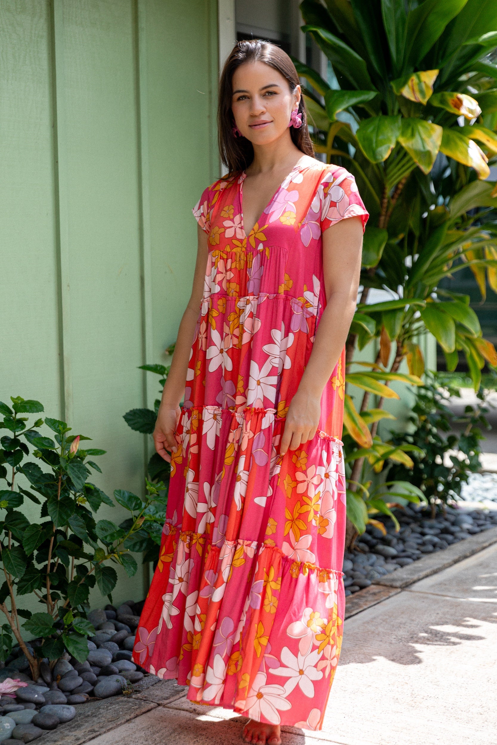 woman with brown hair wearing a pink short sleeve tiered maxi dress with retro flower print