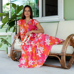 woman with brown hair wearing a pink short sleeve tiered maxi dress with retro flower print