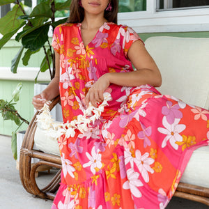 woman with brown hair wearing a pink short sleeve tiered maxi dress with retro flower print