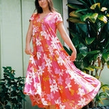 woman with brown hair wearing a pink short sleeve tiered maxi dress with retro flower print