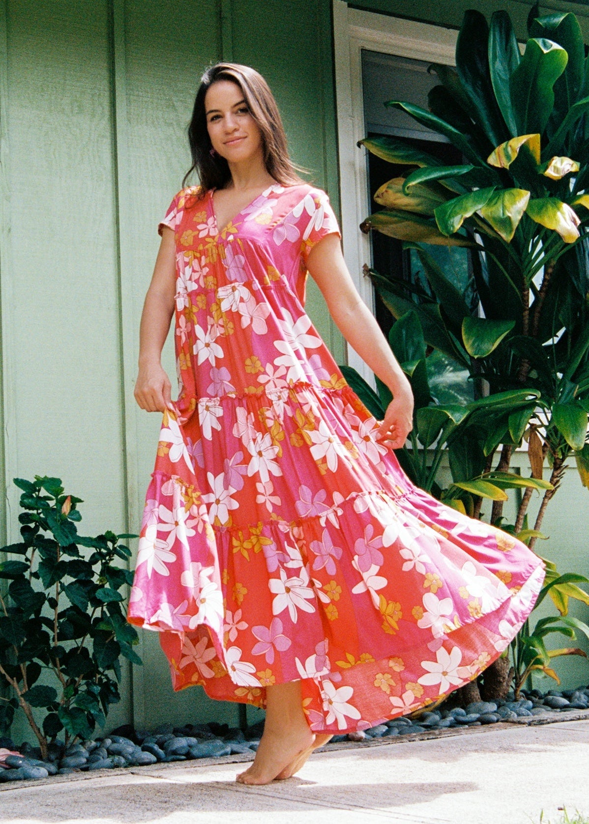 woman with brown hair wearing a pink short sleeve tiered maxi dress with retro flower print