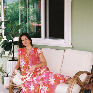 woman with brown hair wearing a pink short sleeve tiered maxi dress with retro flower print